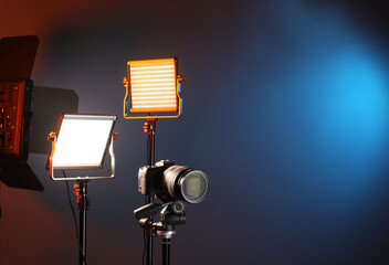 Professional lighting equipment and camera on color background. Space for text