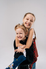 Cheerful sisters hugging and sharing joyful moment, capturing genuine familial bond inside bright professional photography studio with white isolated background. Concept of happy sisterhood and family