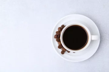 Gordijnen Aromatic coffee in cup, beans and saucer on light table, top view. Space for text © New Africa