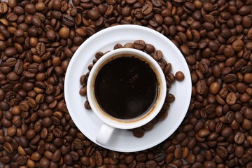 Fototapeta premium Aromatic coffee in cup, saucer and beans, top view