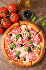 Tasty pizza and ingredients on wooden table, flat lay