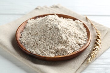Flour and spike on white wooden table, closeup