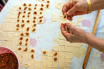 The woman making meaty ravioli ( Turkish: manti ). Manti in Central Asian cuisines are usually larger in size. They are steamed in a multi level metal steamer called mantovarka, mantyshnitsa.	