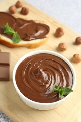 Tasty chocolate hazelnut spread with mint in bowl on grey table