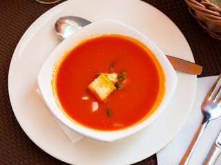 Tomato gazpacho soup with chicken peppers and onions served in bowl with croutons