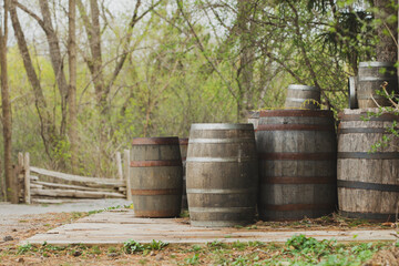 Obraz premium Group of rustic wooden barrels on a wooden deck with natural forest background.