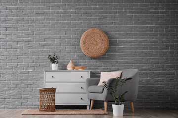 Interior of living room with grey armchair, commode and table