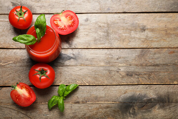 Glass of fresh tomato juice with basil and vegetables on wooden background