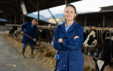 Portrait of successful young woman farmer standing in open cowshed at dairy cow farm..