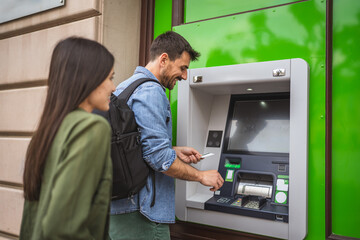 happy travelers couple, withdraw money from the ATM use credit card