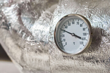 Industrial Pressure Gauge with Metal Housings and Insulation Displaying Measurements in Bar on a Piping System.