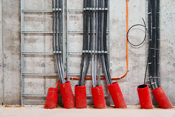 Organized Installation of Multiple Electrical Cables and Conduits Secured to a Concrete Wall with Metal Supports.