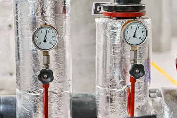 Two Industrial Pressure Gauges with Metal Housings and Insulation Displaying Measurements in Bar on a Piping System.
