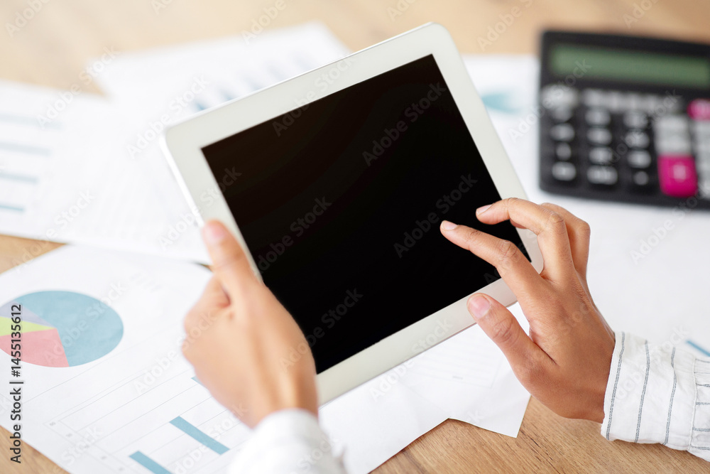 Aufkleber Cropped view of black business lady using tablet computer with blank screen at table with documents, mockup for app or website design. Unrecognizable female CEO working on touch pad, space for text
