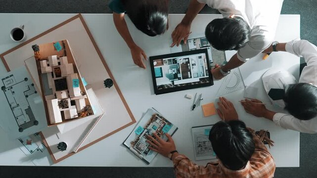 Time lapse of designer looking at model while discussing about building. Top view of architect engineer explaining idea while talking and writing blue print scattering at meeting table. Alimentation.