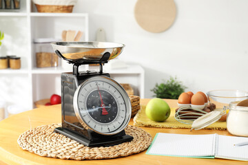 Retro mechanical kitchen scale, products and stationery on wooden table indoors