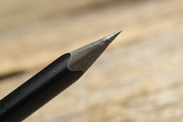 One sharp graphite pencil on wooden table, closeup