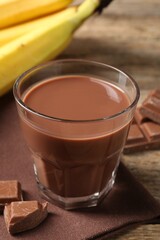 Tasty chocolate milk, pieces and banana on table, closeup