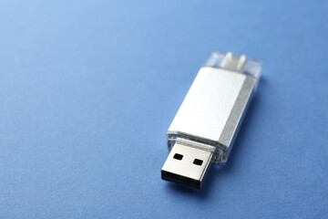 One flash drive on blue background, closeup. Space for text