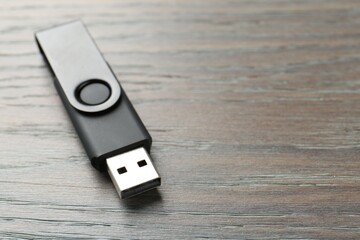 One flash drive on wooden background, closeup. Space for text