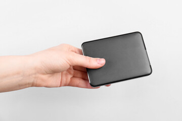 Man with external hard drive on light grey background, closeup