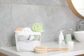 Clean towels in basket, cosmetic products and brush on vanity indoors