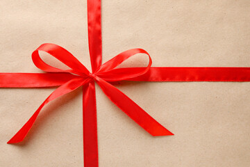 Gift wrapped in kraft paper and bow as background, top view