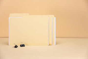 File folders with papers and binder clips on pale yellow background, space for text