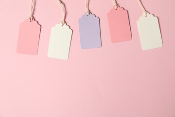 Blank tags with strings on pink background, flat lay. Space for text