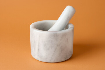 Marble mortar and pestle on light brown background, closeup
