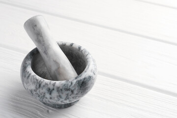 Marble mortar and pestle on white wooden table, closeup. Space for text