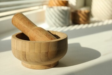 Wooden mortar and pestle on windowsill indoors, closeup. Space for text