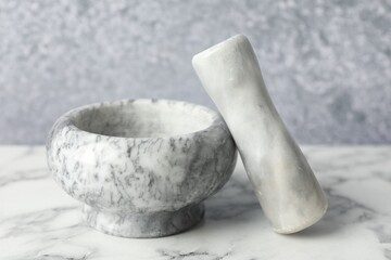 Mortar and pestle on white marble table, closeup