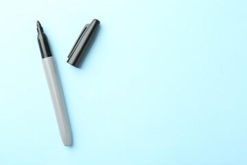 One black marker on light blue background, top view. Space for text