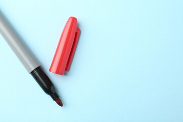 One red marker on light blue background, top view. Space for text