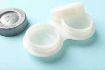 Contact lenses in case on light turquoise background, closeup