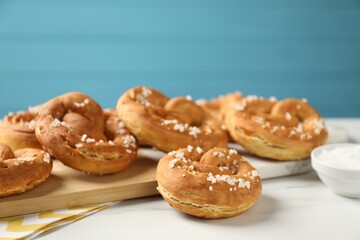 Tasty pretzels with salt on white marble table, closeup