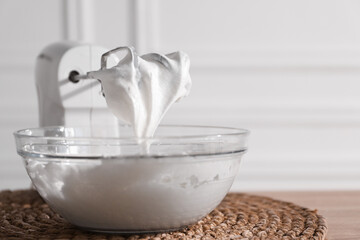 Hand mixer with whisks and bowl of whipped cream on table, closeup. Space for text