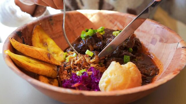 Young woman eating Caribbean oxtail, Jamaican fried dumpling and fried sweet plantain