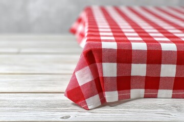 Red and white checkered tablecloth draped on a wooden table. Rustic and charming, perfect for a picnic or casual dining.