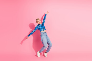Vibrant young woman posing gracefully against a cheerful pink background in stylish blue top and...