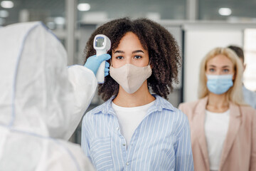 New normal during outbreak of covid-19. Checking temperature of multiracial workers in protective...