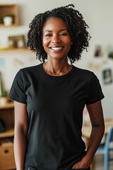 Fototapeta premium Portrait of a smiling woman with short curly hair wearing a plain black t-shirt, hands in pockets, in a casually decorated home interior.