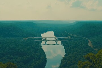 High angle view of a bridge spanning a river valley, surrounded by lush green forests.  Misty mountains in the distance