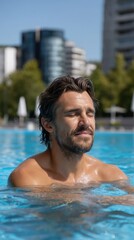 Relaxed man with wet hair enjoying the bright sunshine in a refreshing outdoor swimming pool on a warm day