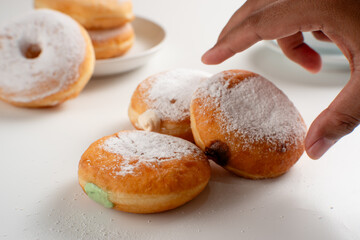 Powdered jelly-filled donuts with creamy fillings on white background – sweet pastry dessert perfect for bakery, breakfast, recipes, articles, snack-theme or any cooking content.