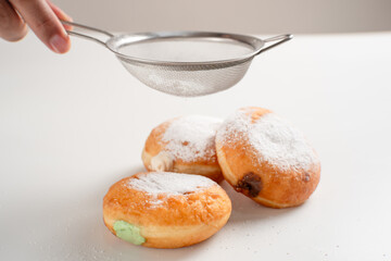 Powdered jelly-filled donuts with creamy fillings on white background – sweet pastry dessert perfect for bakery, breakfast, recipes, articles, snack-theme or any cooking content.