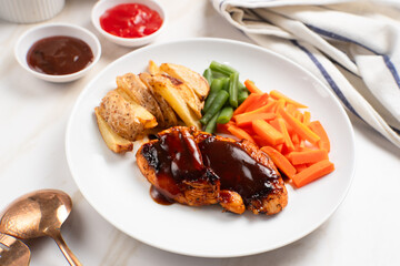 Grilled chicken steak with barbecue sauce, potato wedges, and fresh vegetables. Perfect for healthy lunch, dinner menu content, recipes, articles or any cooking content