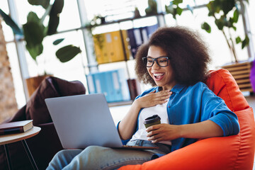 Young female professional with laptop enjoying a casual workspace moment with coffee