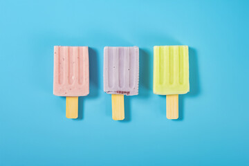 top view strawberries and blue berries and hami melon flavors popsicles melting process on a blue background